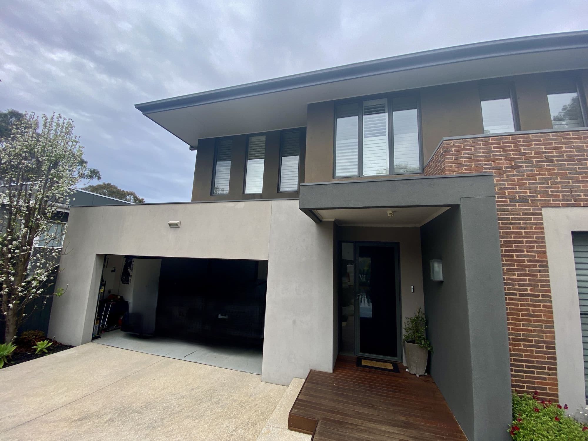 Modern charcoal home exterior with a timber-lined entry and garage