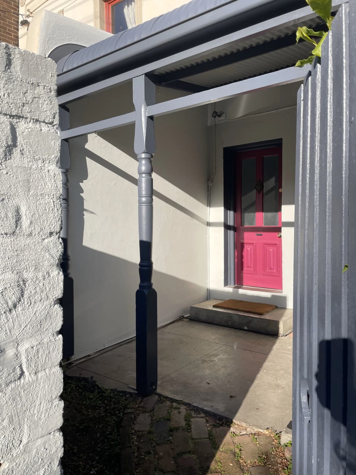 Restored period veranda with grey post and pink front door — Tricoat heritage work